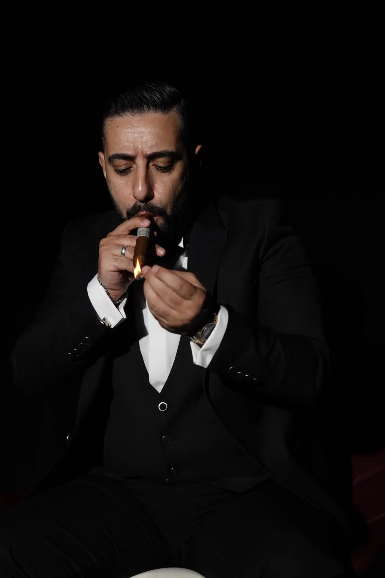 يُشعل سيجارًا في الظلام، واللهب يضيء وجهه
