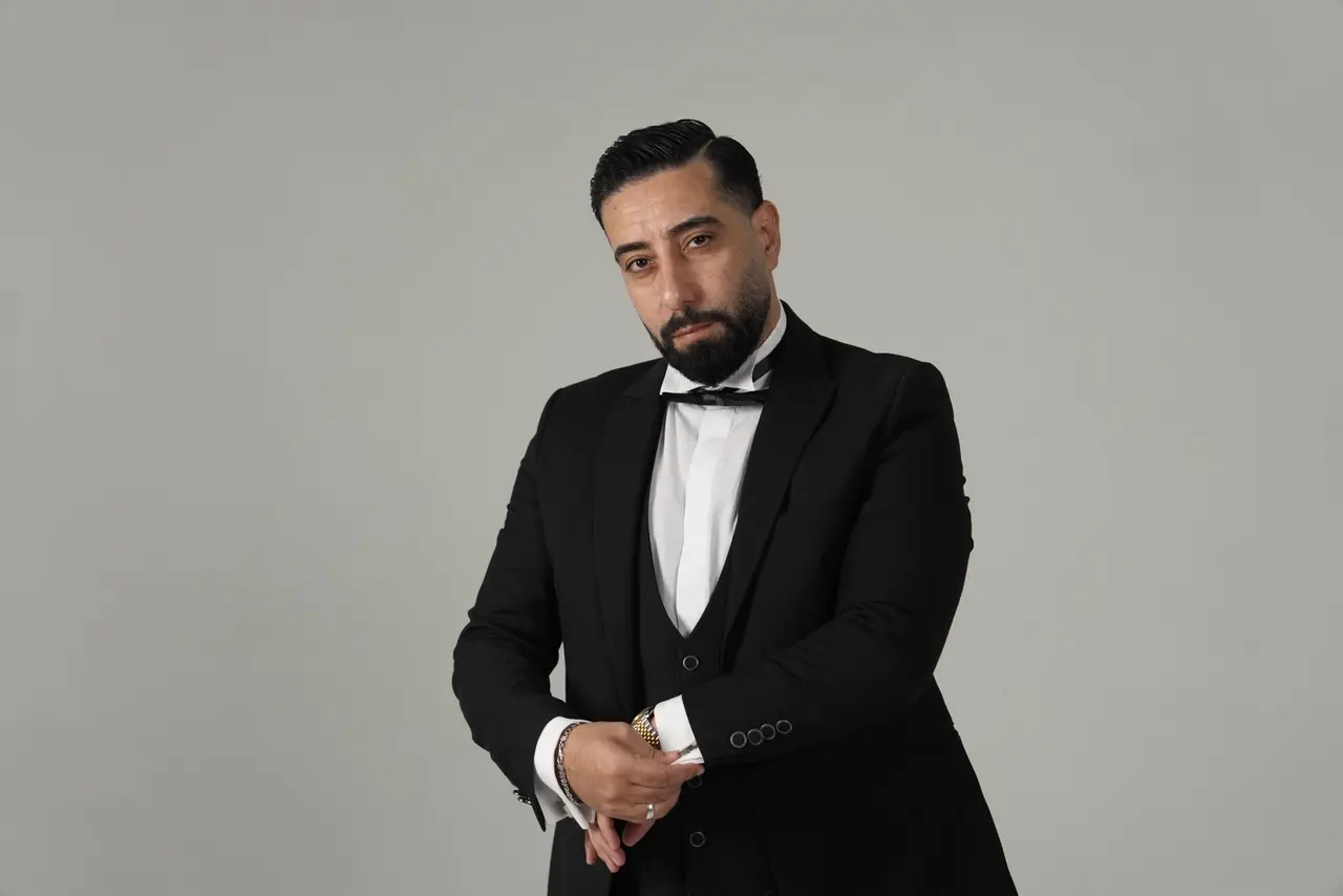 يعدّل زرّ الكُم أمام خلفية استوديو رمادية